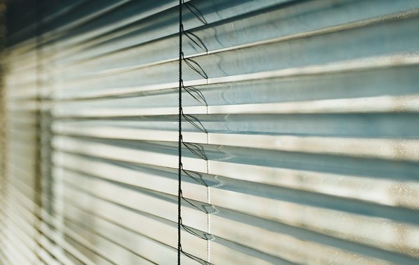 Jaluzele orizontale albe din aluminiu cu lumina filtrată printre lamele